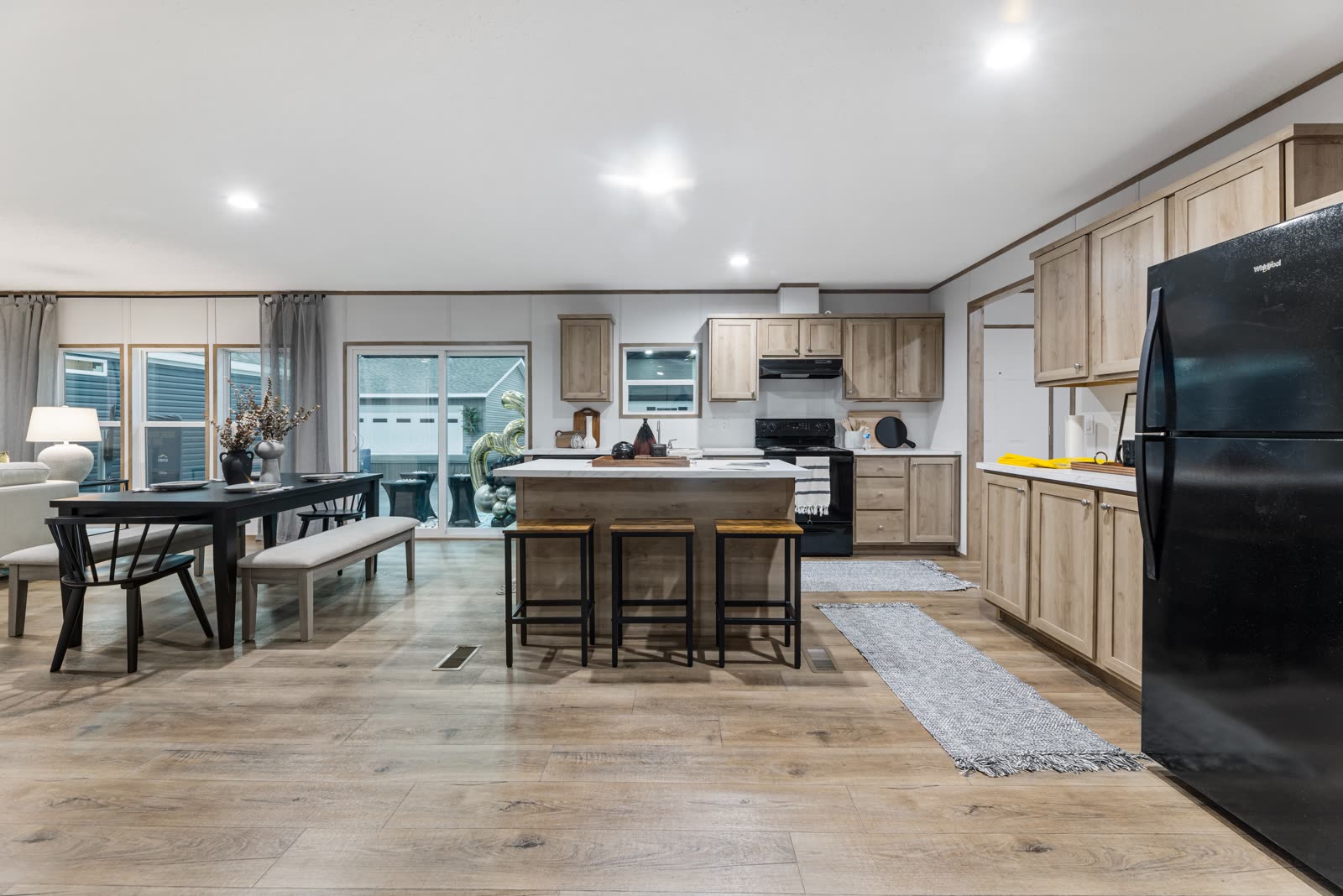 Kitchen and dining. Oak cabinets, white counters, black appliances.