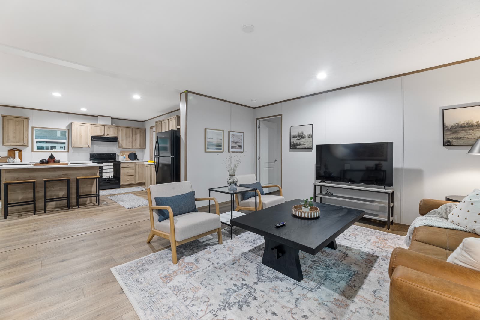 Living room toward the kitchen. Leather sofa, cream armchairs.
