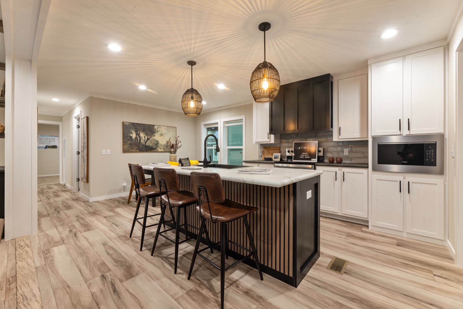 Kitchen. Island with seating, white cabinets, dark hood, built-in microwave.