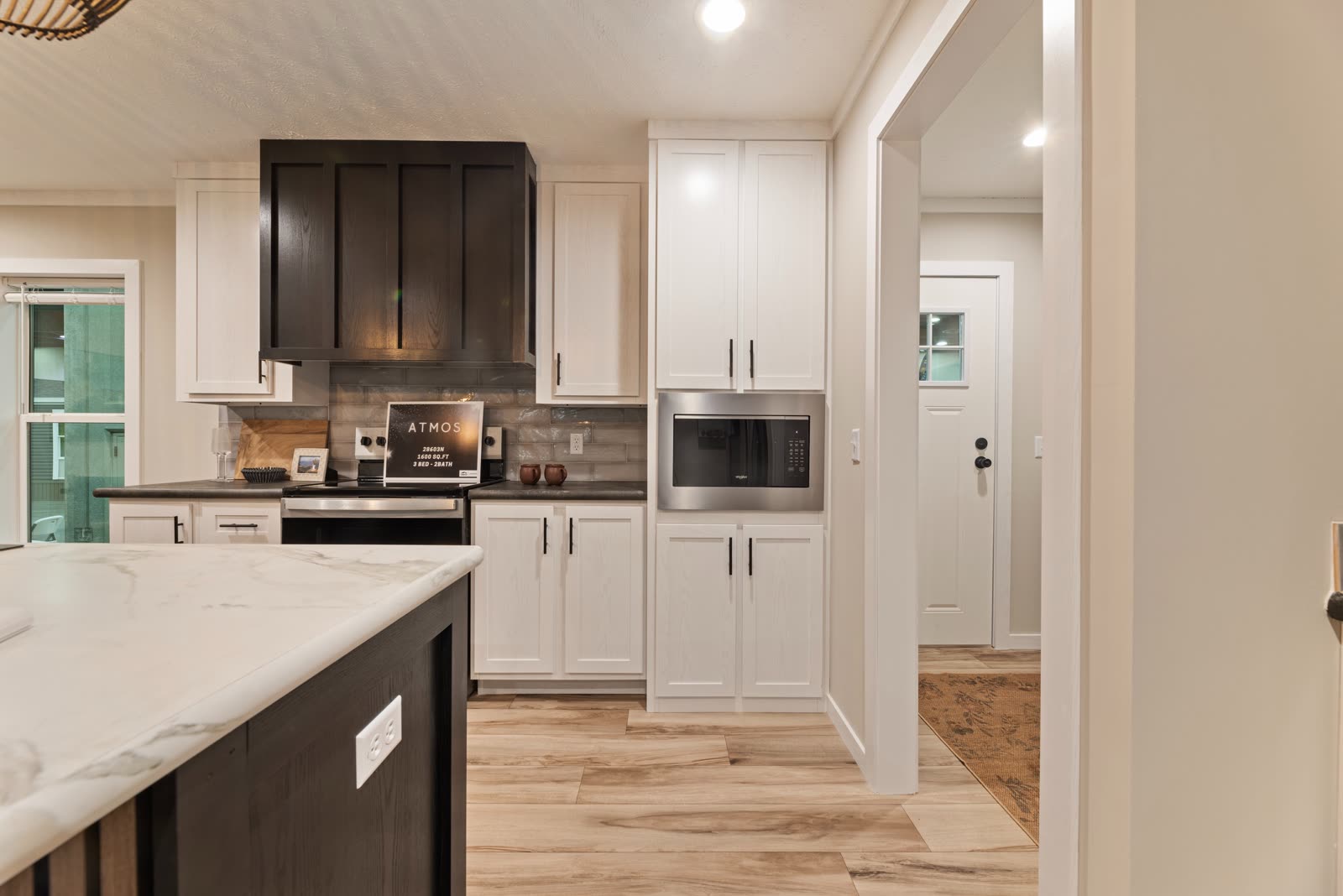 Kitchen. Range under the dark hood, microwave, doorway to the utility room.