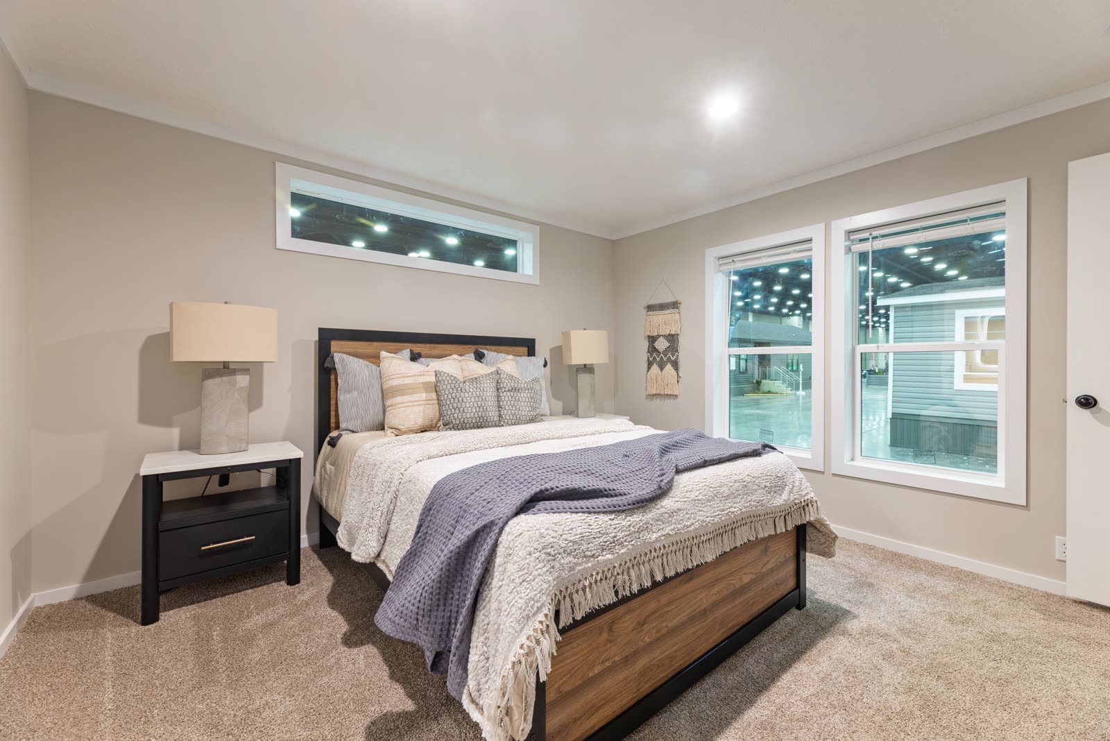 Bedroom 1. Bed with black nightstands, transom window, windows to the lot.