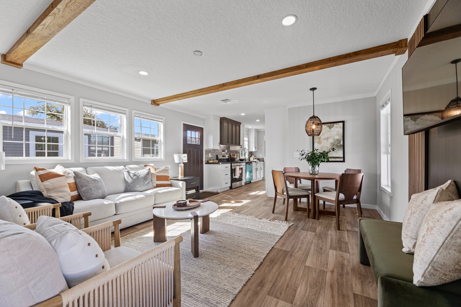 Living room toward the kitchen. Sectional sofa, dining table, front door.