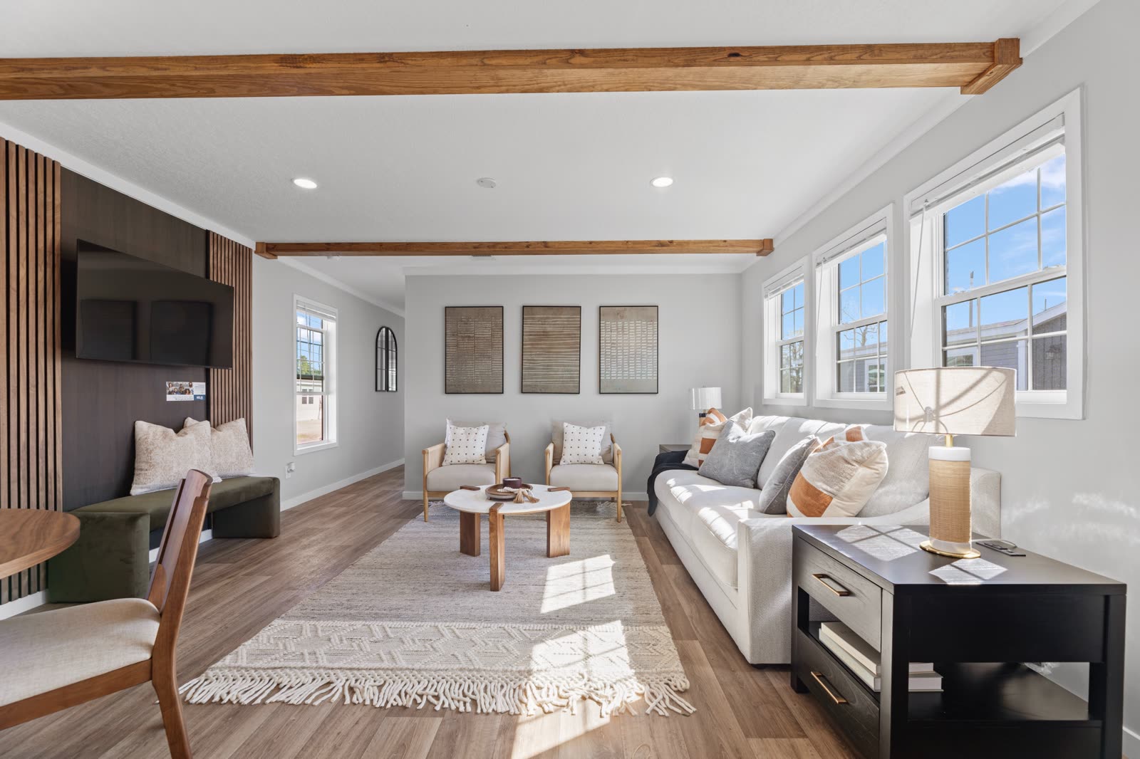 Living room. Sofa, two armchairs, slat accent wall with television, three windows.