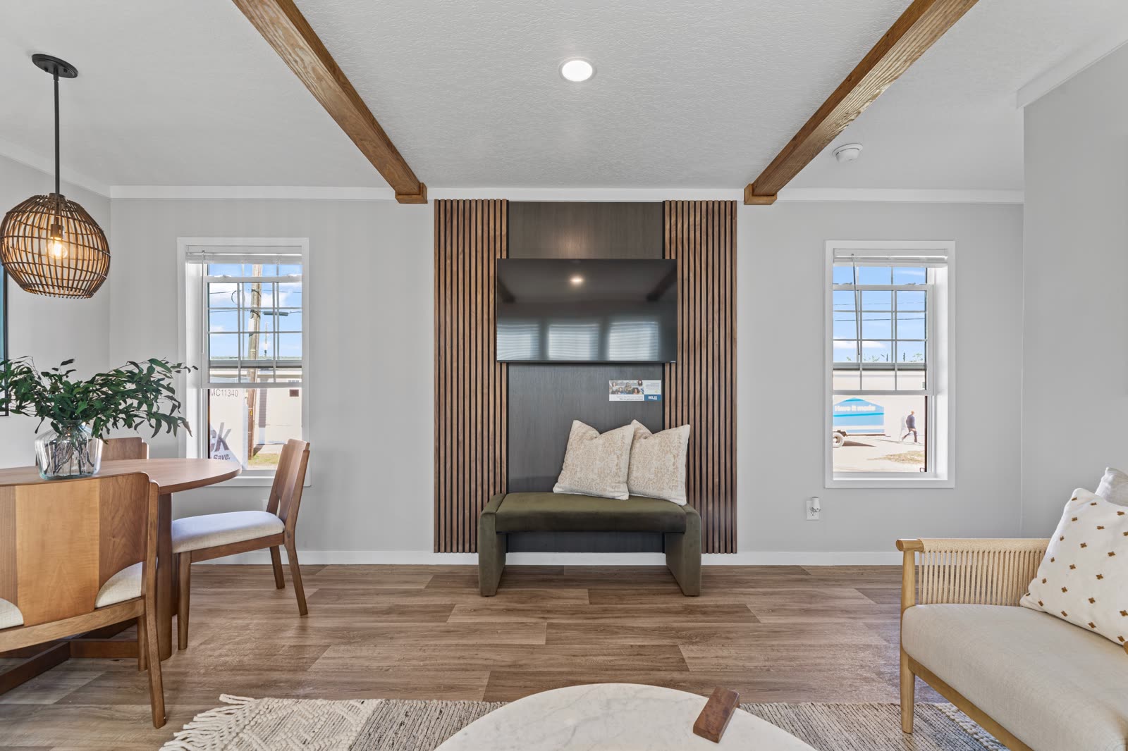 Living room. Slat accent wall with television and bench, dining table at left.