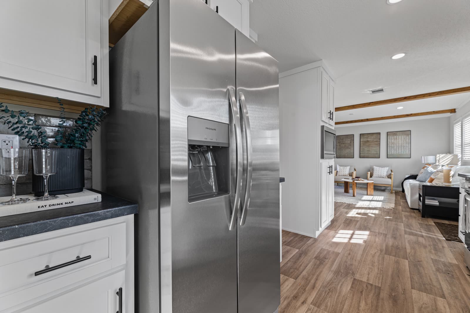 Kitchen. Stainless refrigerator, dark counter, living room beyond.