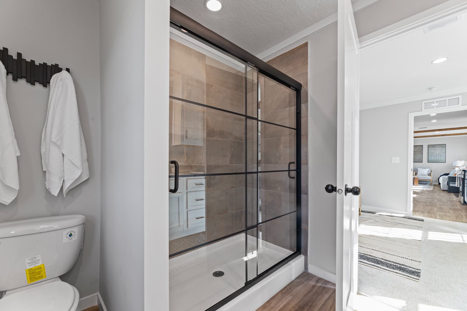 Bath 1. Walk-in shower with glass door, toilet, bedroom beyond the door.