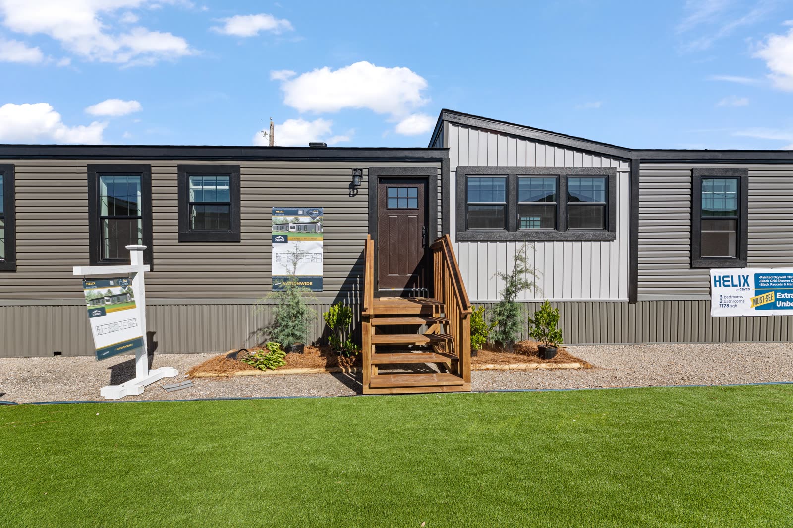 Exterior on the lot. Dark grey lap siding, board-and-batten dormer, wood entry steps.