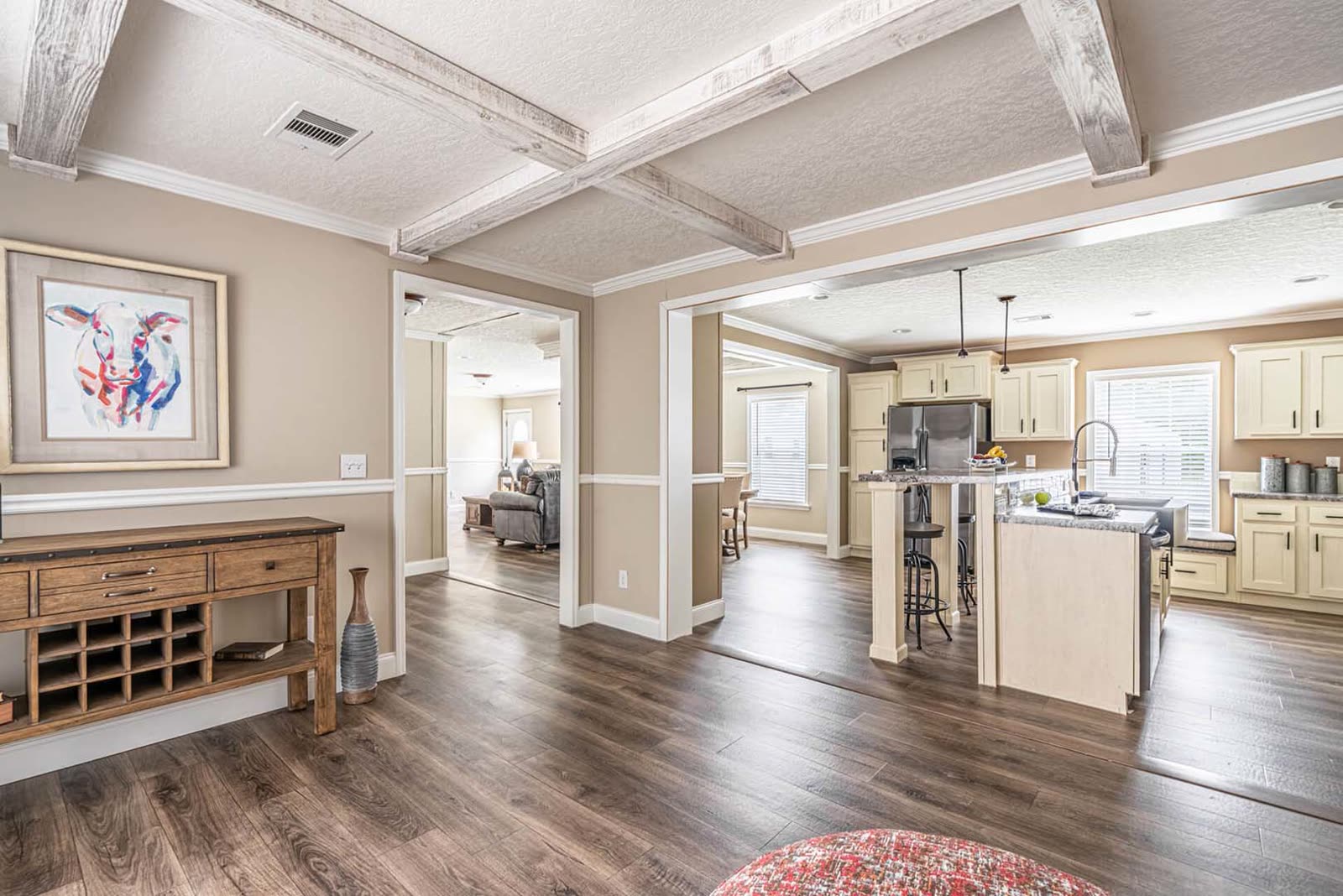Dining room toward the kitchen. Console table with wine rack, coffered ceiling, island beyond.