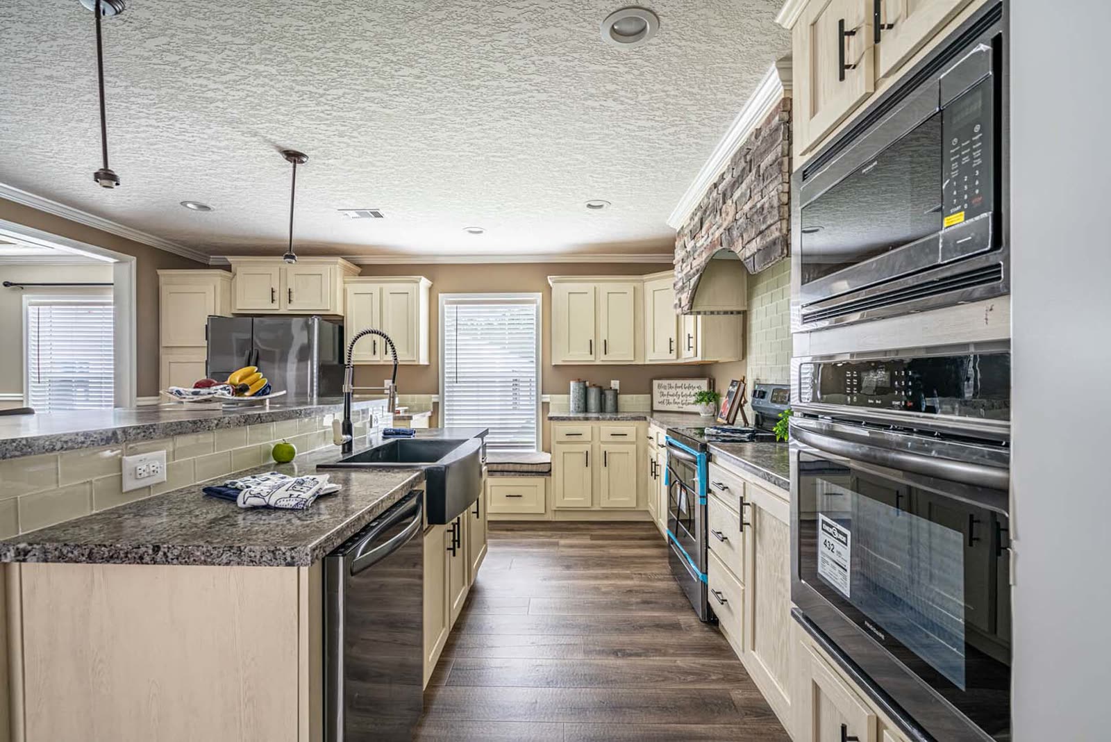 Kitchen. Island with sink, stone hood surround, wall oven and microwave at right.