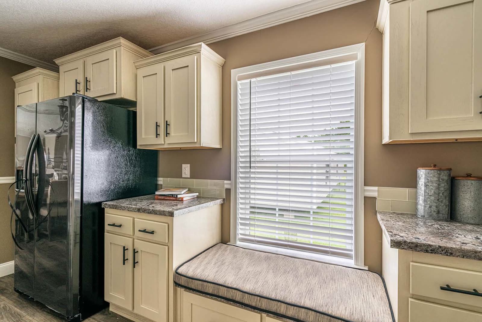 Kitchen. Window seat under the window, refrigerator at left, granite counters.
