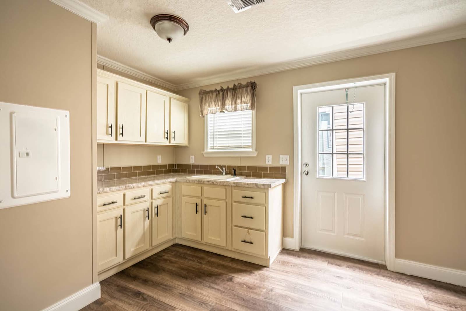 Utility room. Cabinets, counter with sink, exterior door, electrical panel.