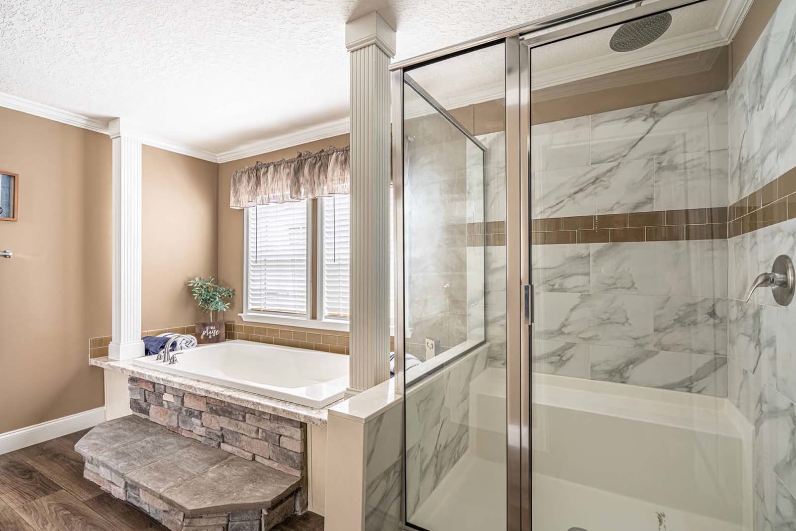 Master bath. Tub with stone step and marble-look tiled shower.