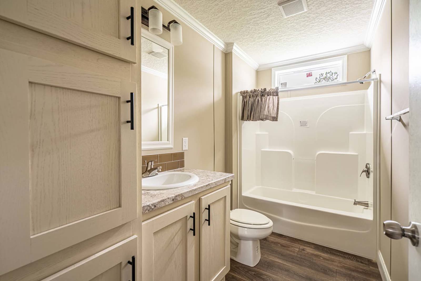 Bath 2. Vanity, toilet, tub and shower unit, window.
