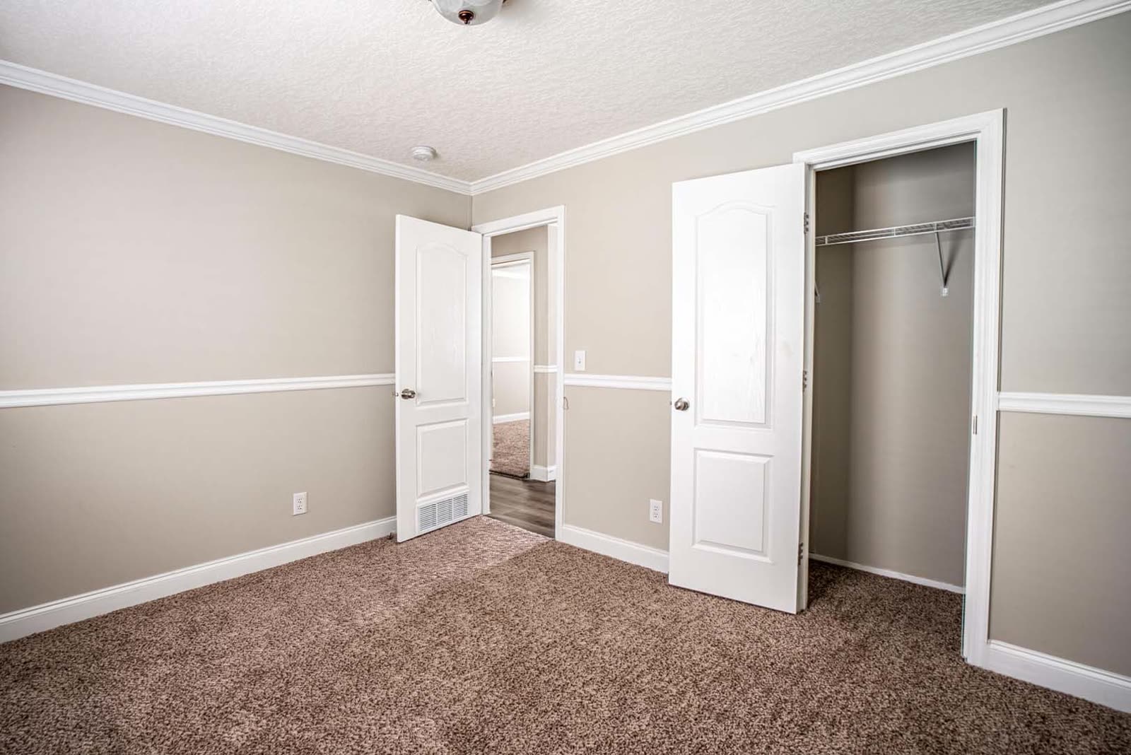 Bedroom. Empty, carpet, closet with bifold doors, door to the hall.