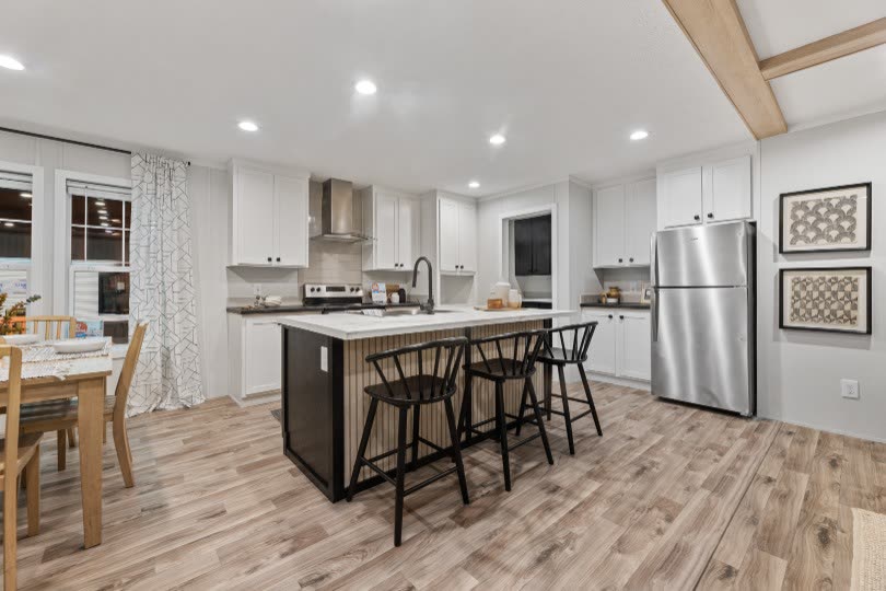 Kitchen. Island with stools, refrigerator, dining table at left.