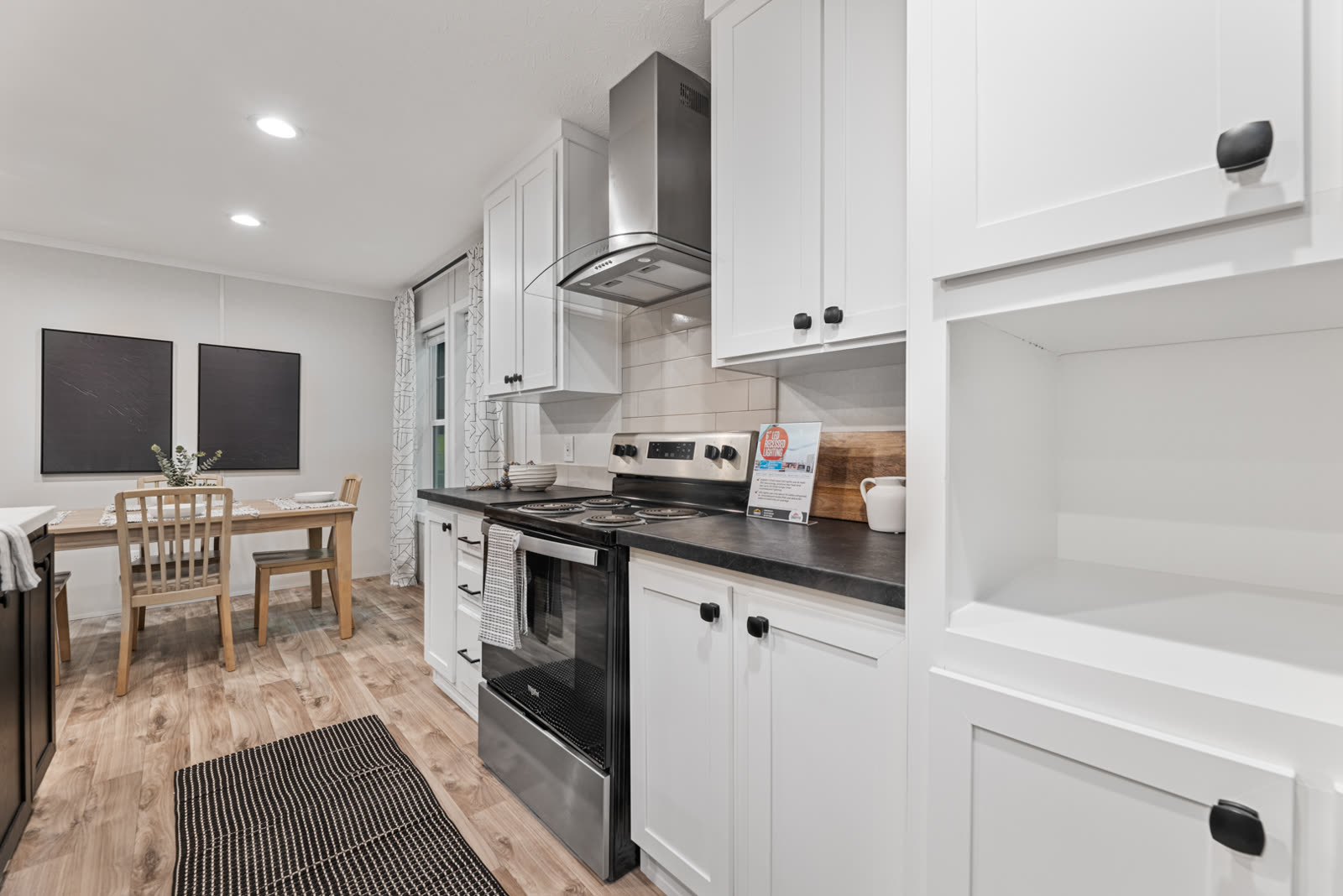 Kitchen. Range under the hood, dark counters, dining table by the window.