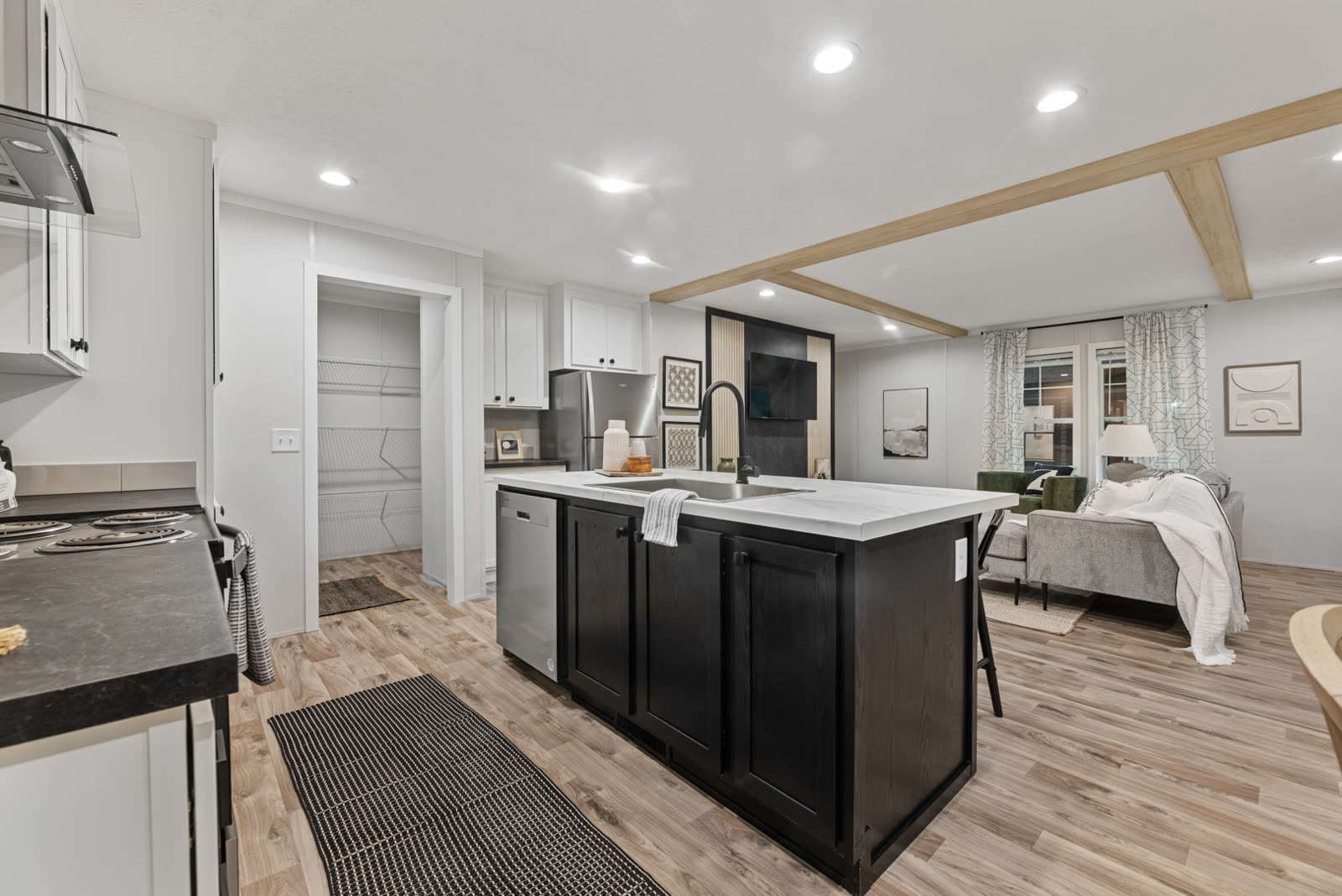 Kitchen toward the living room. Island with sink and dishwasher, pantry doorway at left.