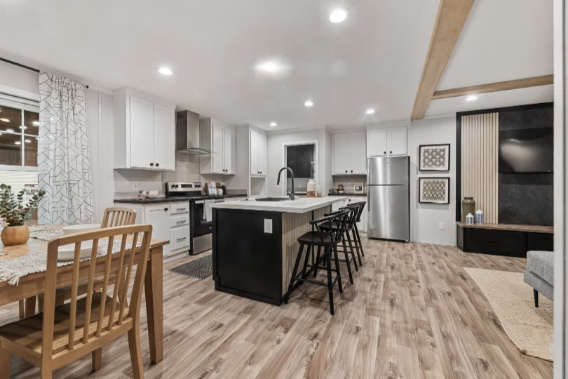 Dining and kitchen. Table, island, refrigerator, television wall at right.
