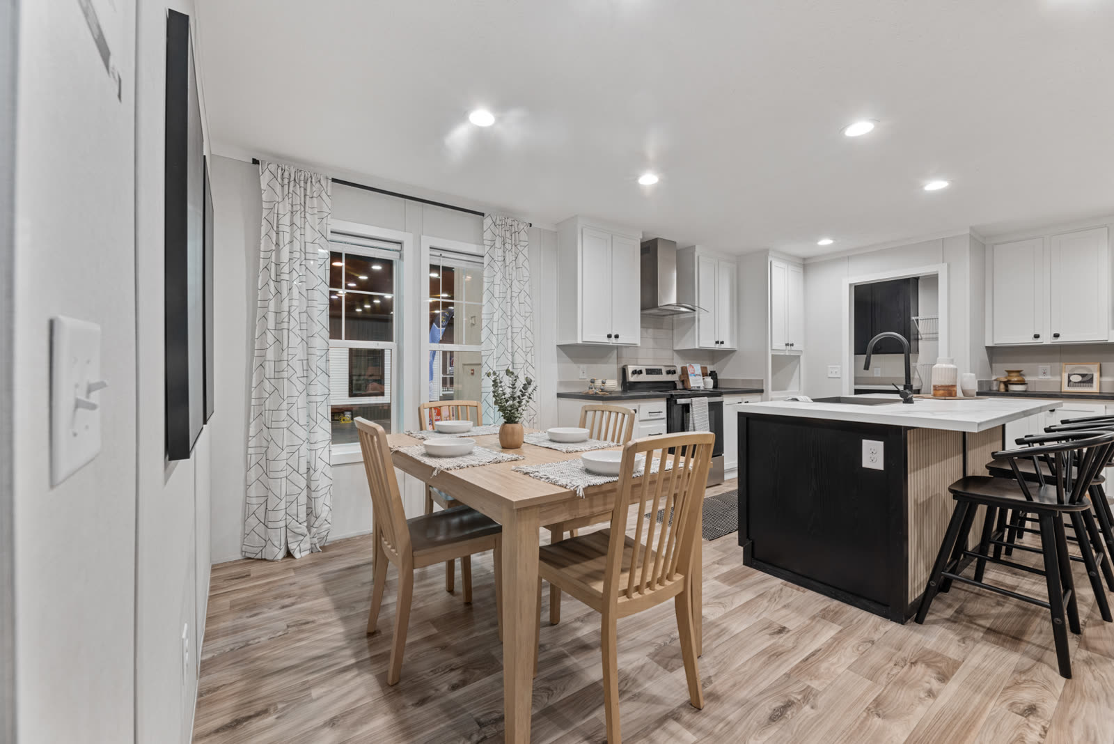 Dining. Light wood table beside the windows, island at right.