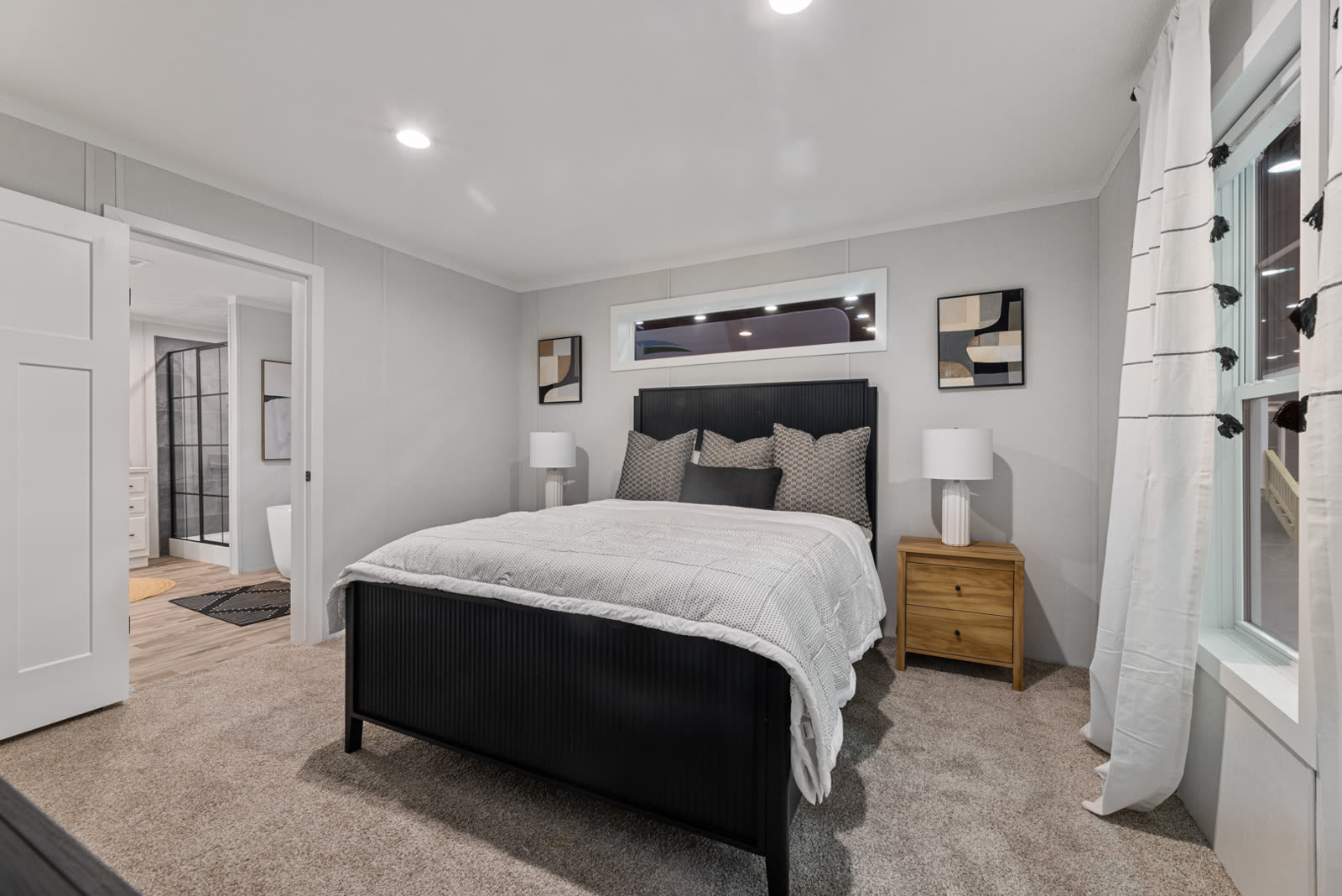 Bedroom 1. Black bed, wood nightstands, transom window, door to Bath 1 at left.