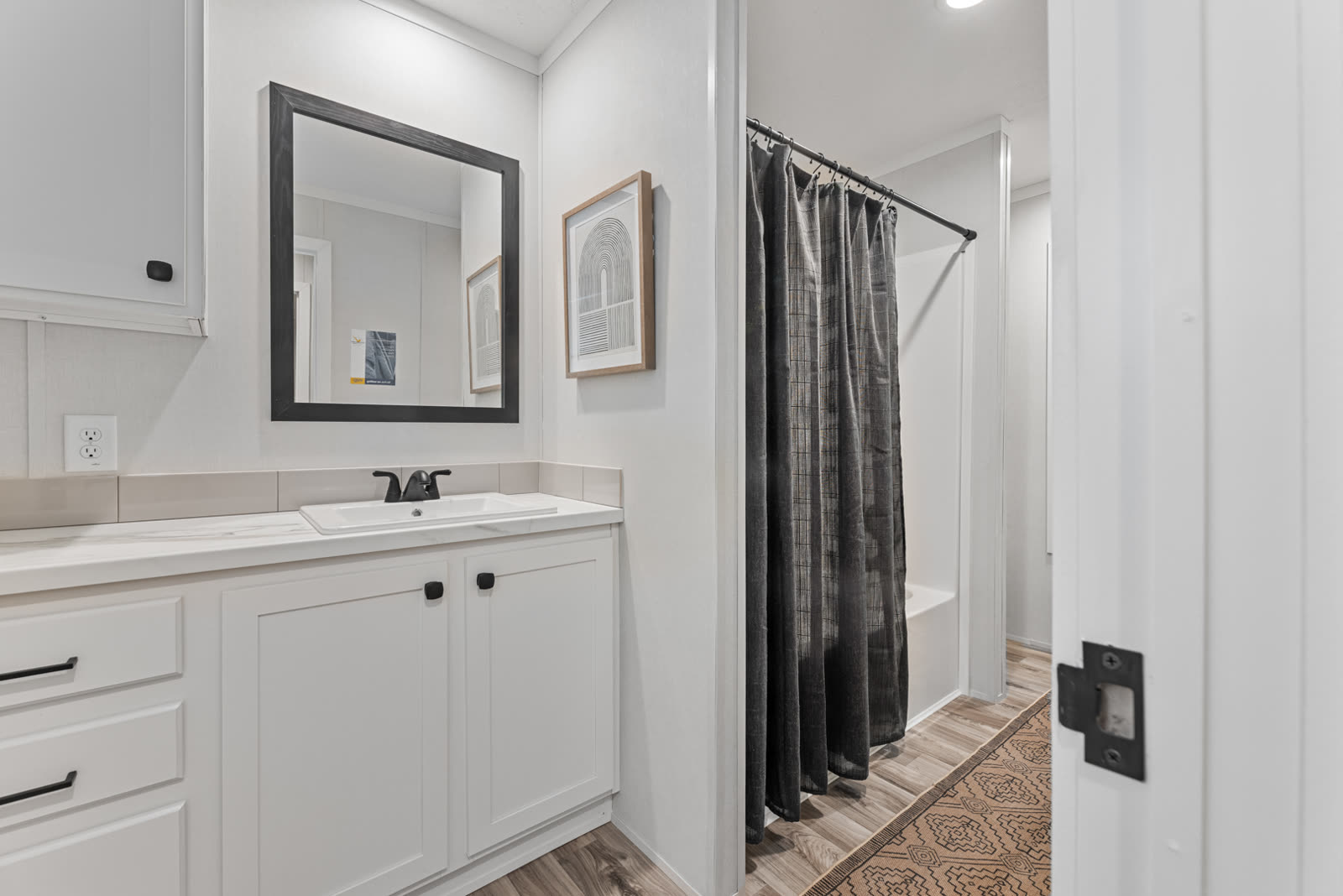 Bath 2. Vanity with mirror, tub with shower curtain.