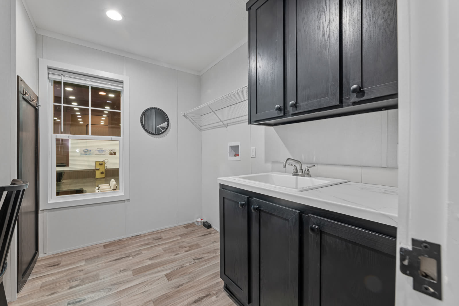 Utility room. Sink, dark cabinets, drying rod, window.