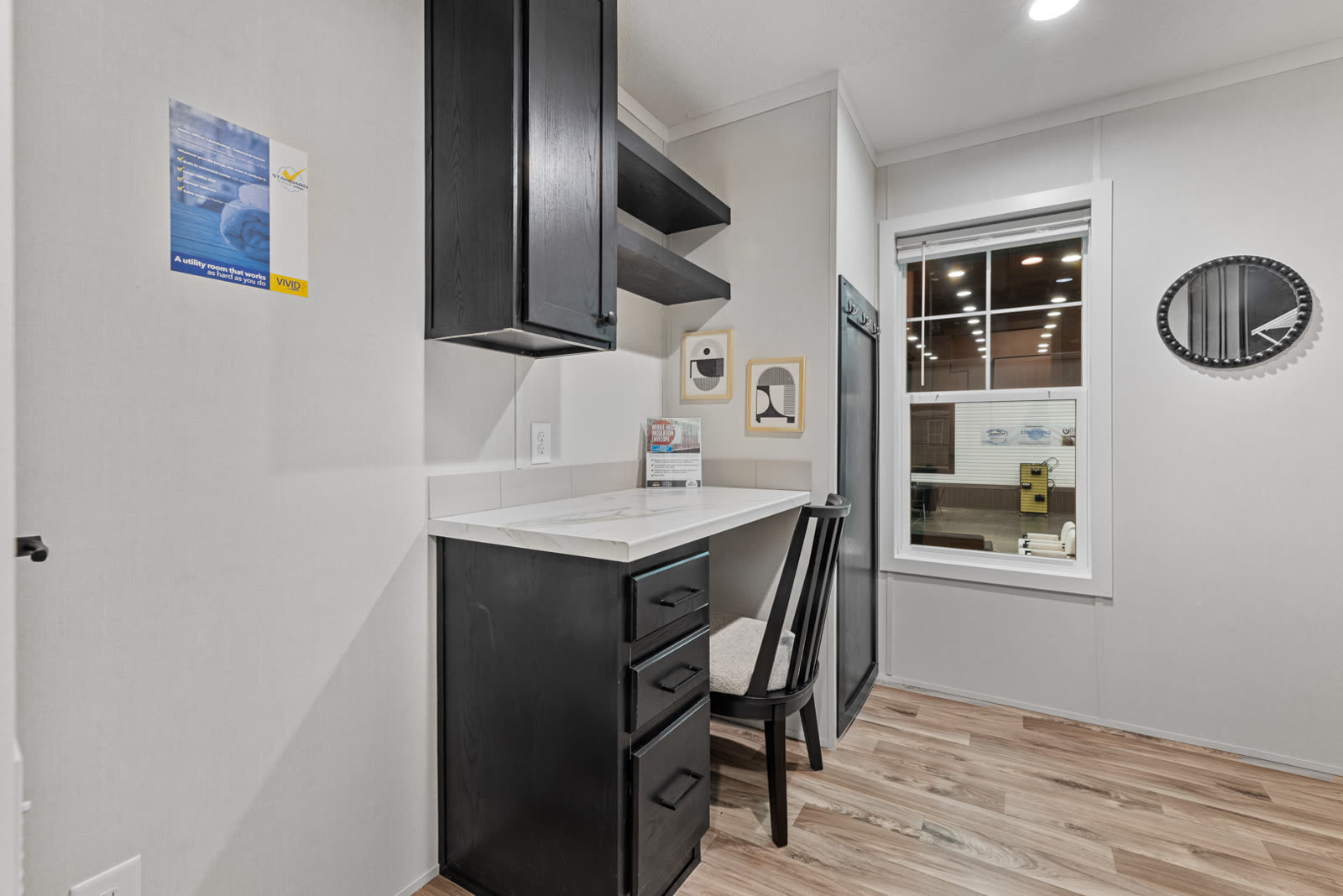 Utility room. Built-in desk, dark cabinets, open shelves, window.