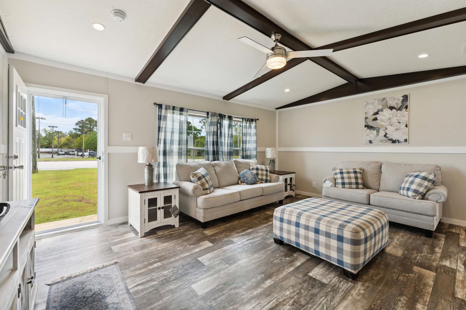 Living room, first furnishing. Front door open to the yard, sofa under the window.