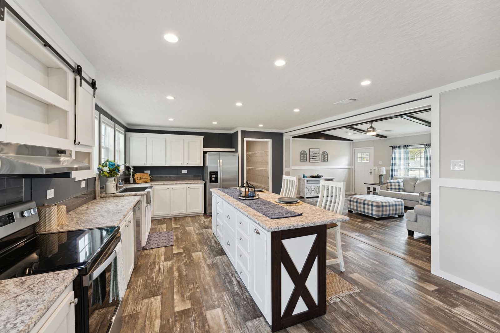 Kitchen toward the living room, first furnishing. Range at left, island, sofa beyond.