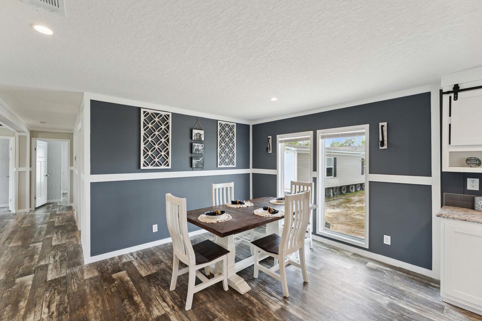 Dining, first furnishing. Navy walls, table and chairs, sliding glass door, barn door at right.