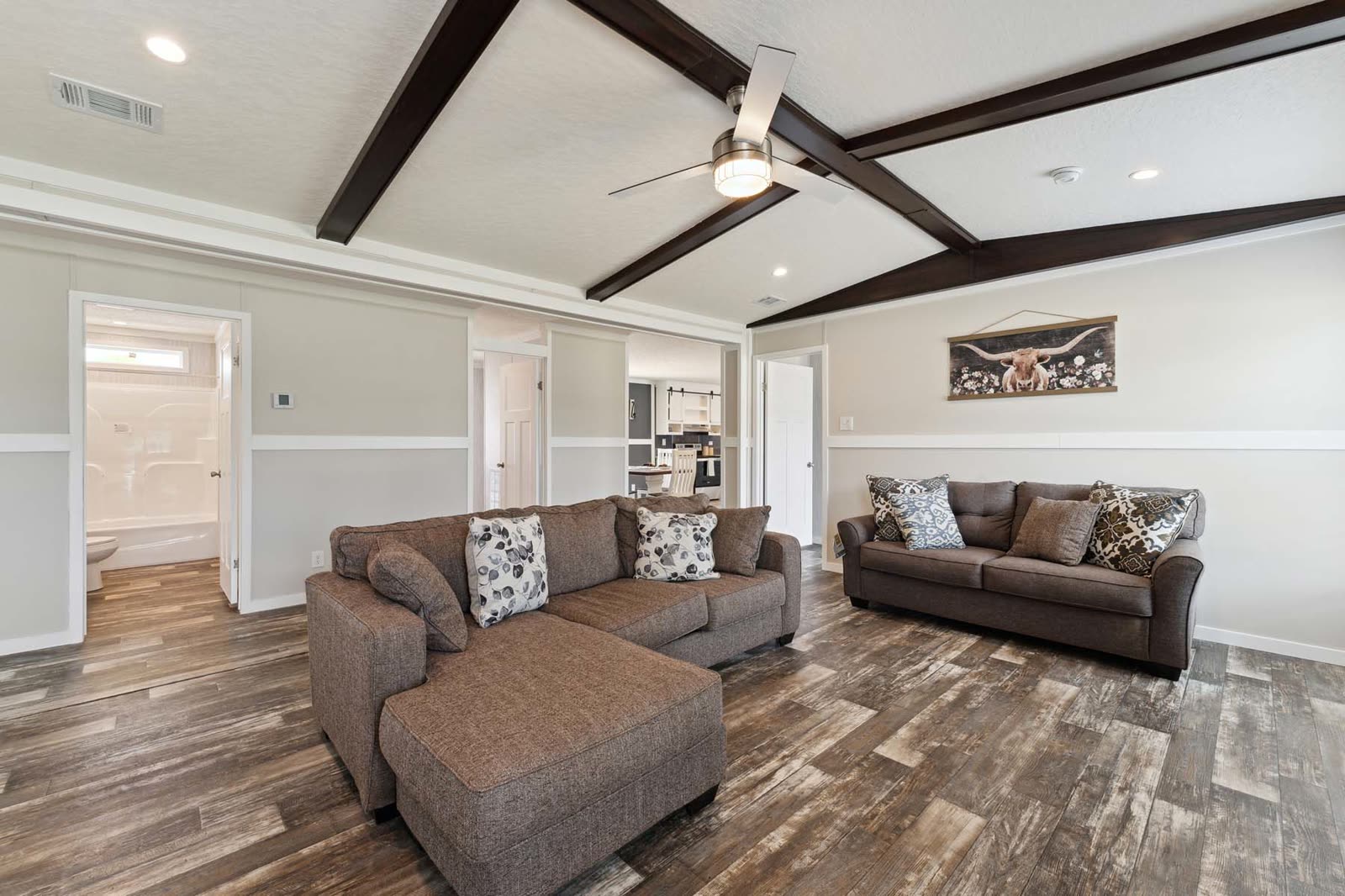Family room, first furnishing. Sectional and loveseat, bath and bedroom doors beyond.