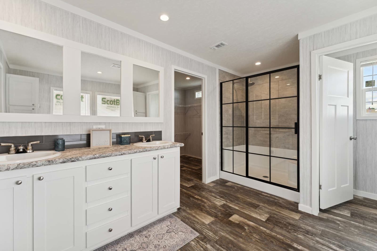 Primary bath. Double vanity, glass-panel shower, walk-in closet beyond.