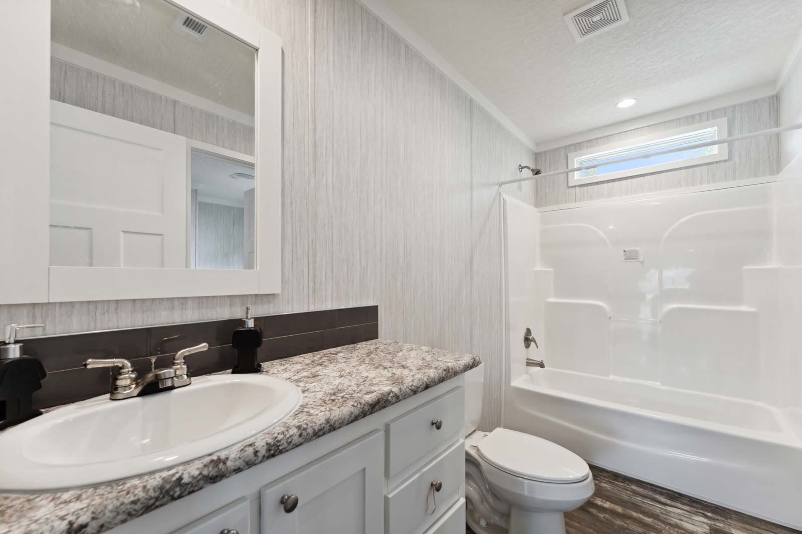 Bath 2. Single vanity, toilet, tub with shower, high window.