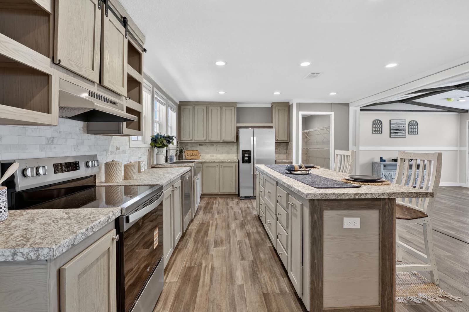Kitchen. Range and hood, island, refrigerator, living room beyond.
