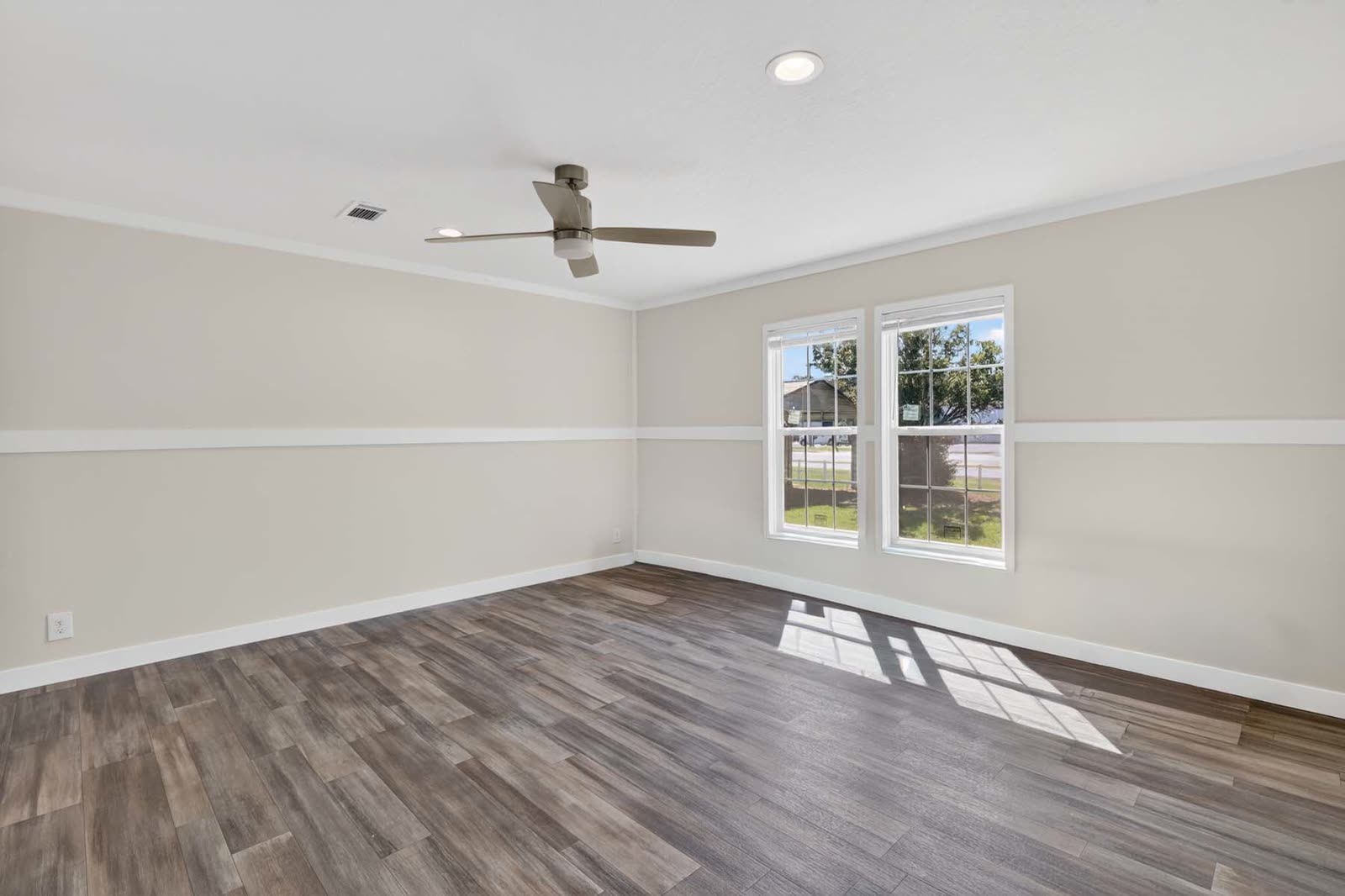 Primary bedroom. Empty, ceiling fan, double window.