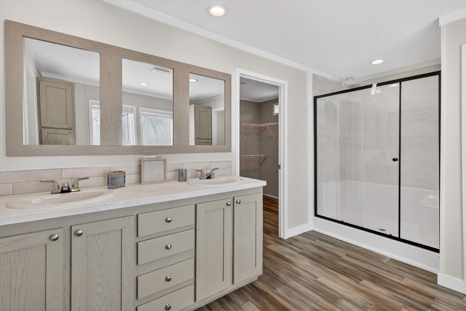 Primary bath. Double vanity, framed mirror, glass shower, closet beyond.