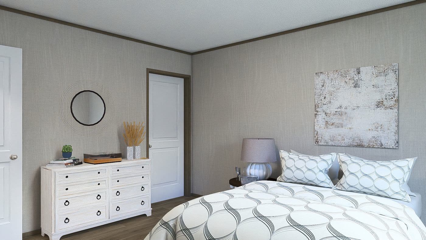 Primary bedroom. White dresser with round mirror, patterned bedding.