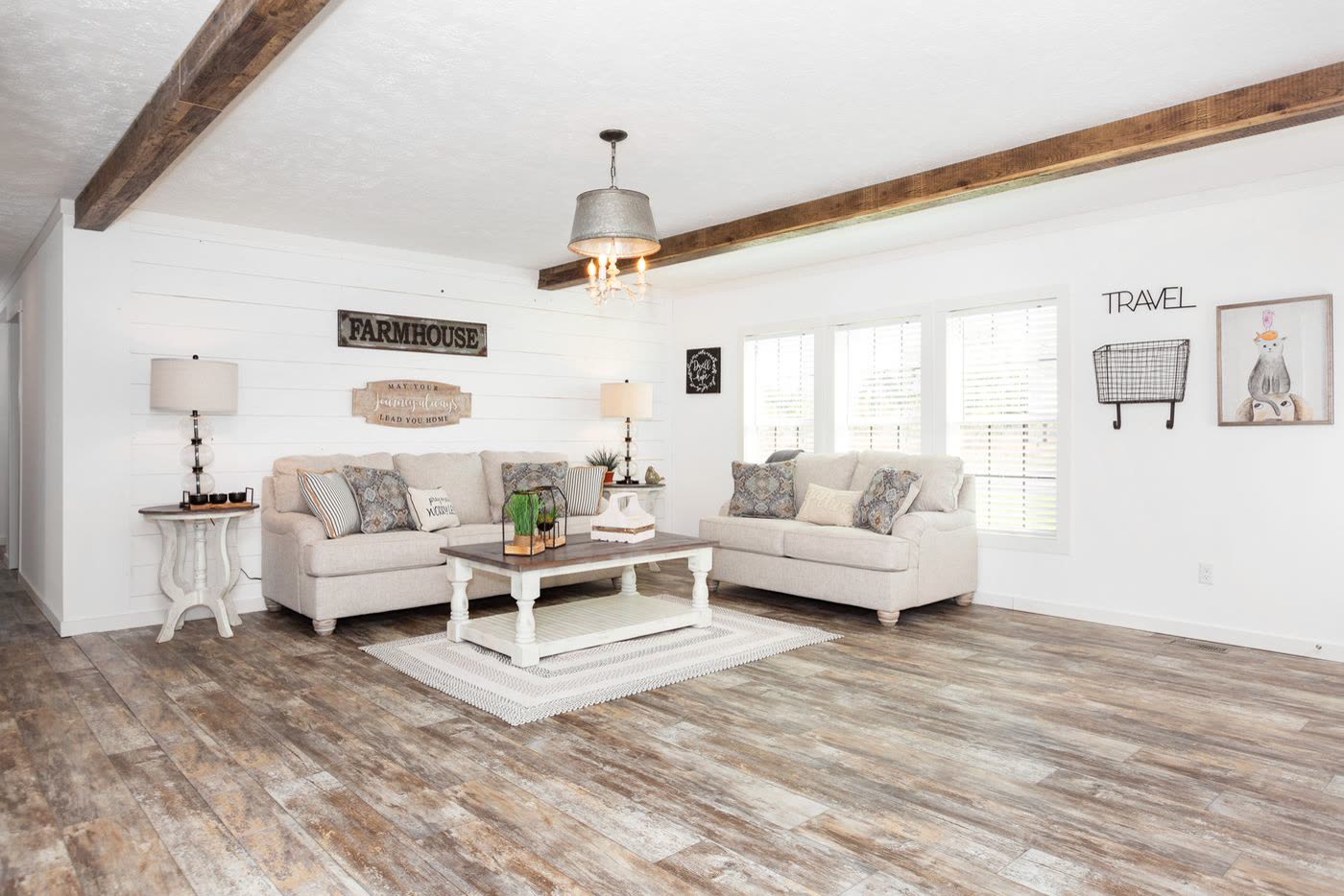 Living room. Two cream sofas, white coffee table, shiplap wall, beam ceiling.