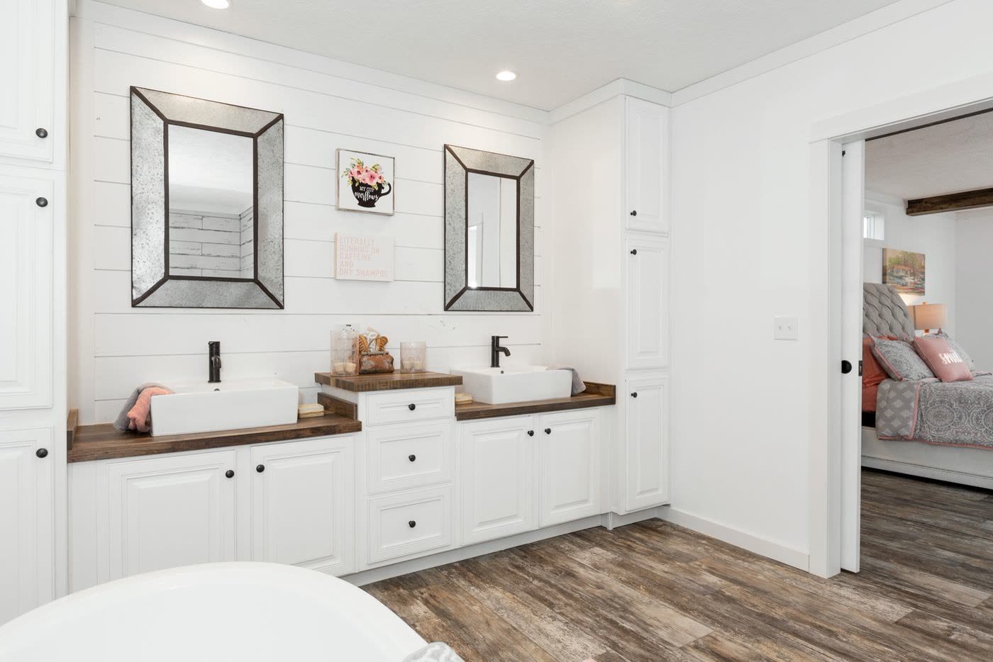 Primary bath. Double vessel sinks on a wood counter, two mirrors, door to the bedroom.