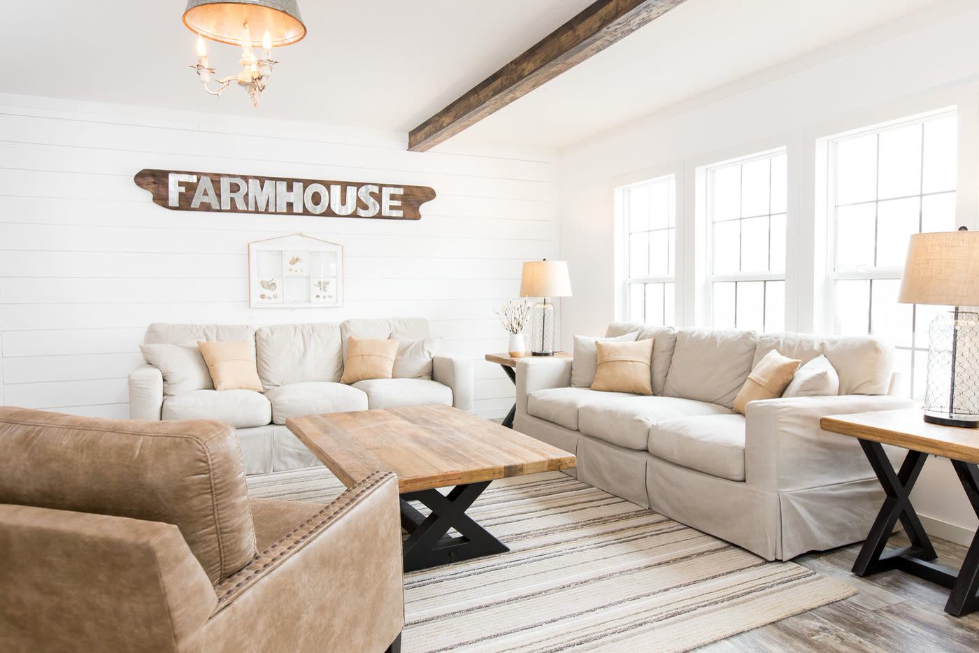 Living room, second furnishing. Cream sofas, leather armchair, wood coffee table under the Farmhouse sign.