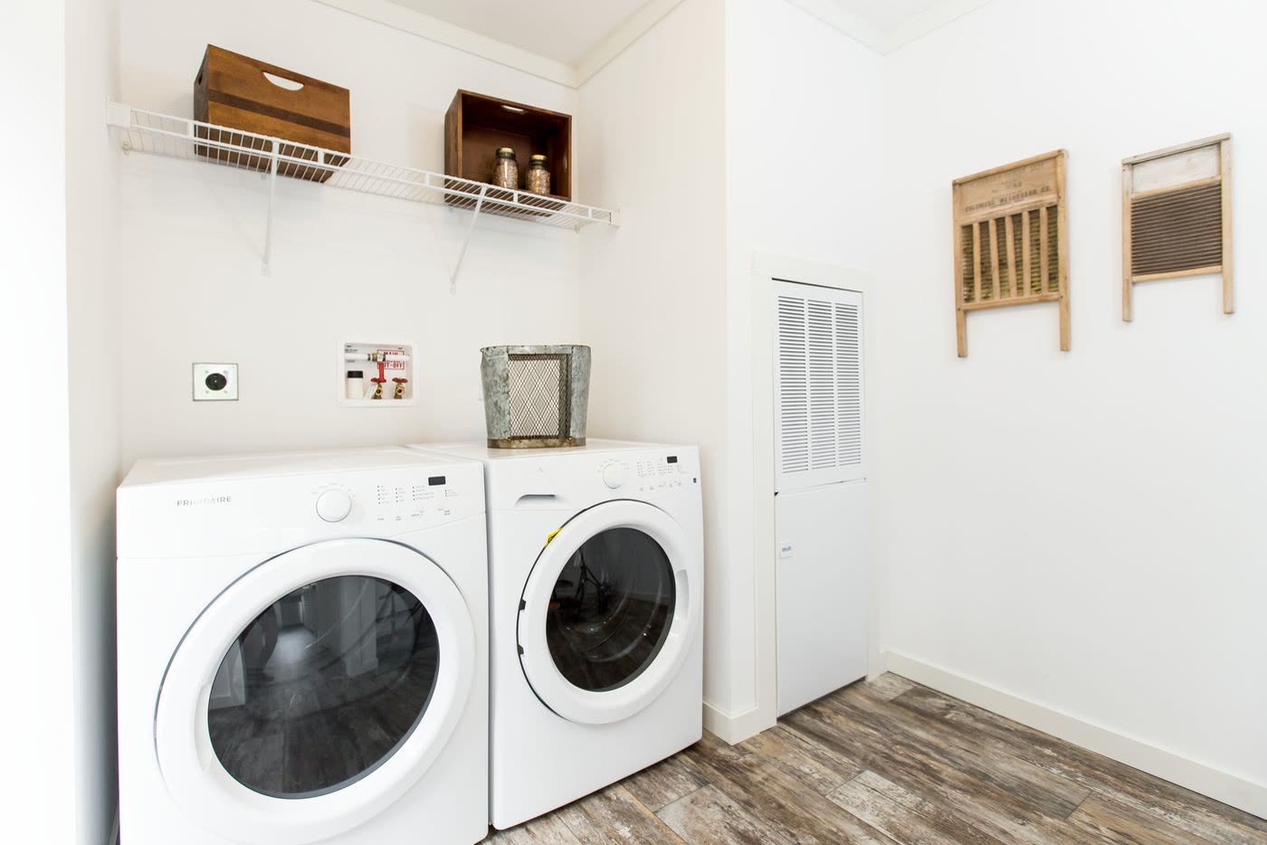 Utility room. Washer and dryer, wire shelving, louvered door.