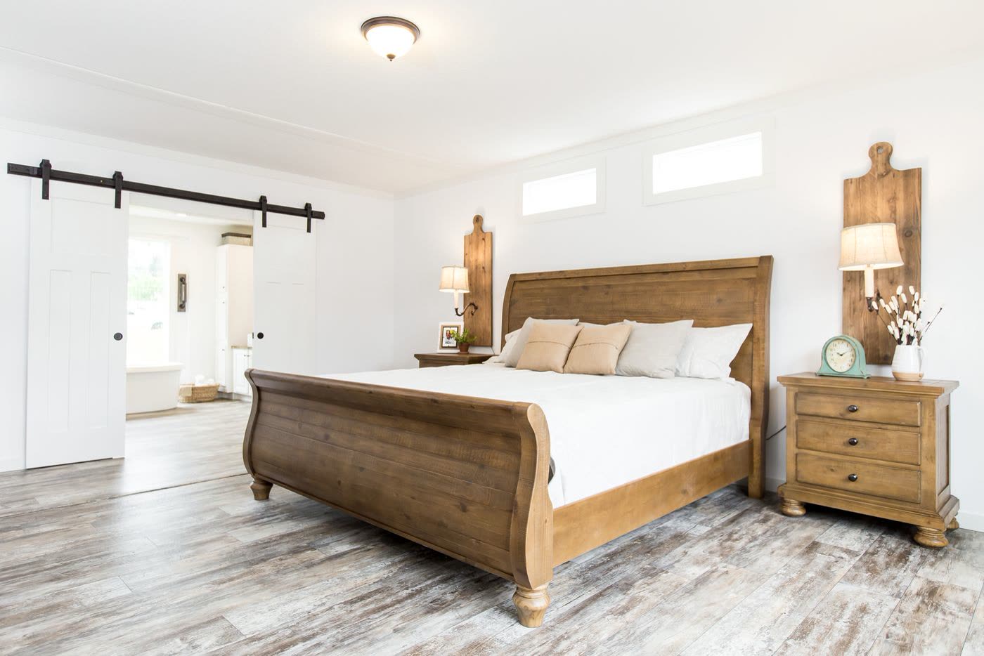 Primary bedroom, second furnishing. Wood sleigh bed, barn door to the bath.