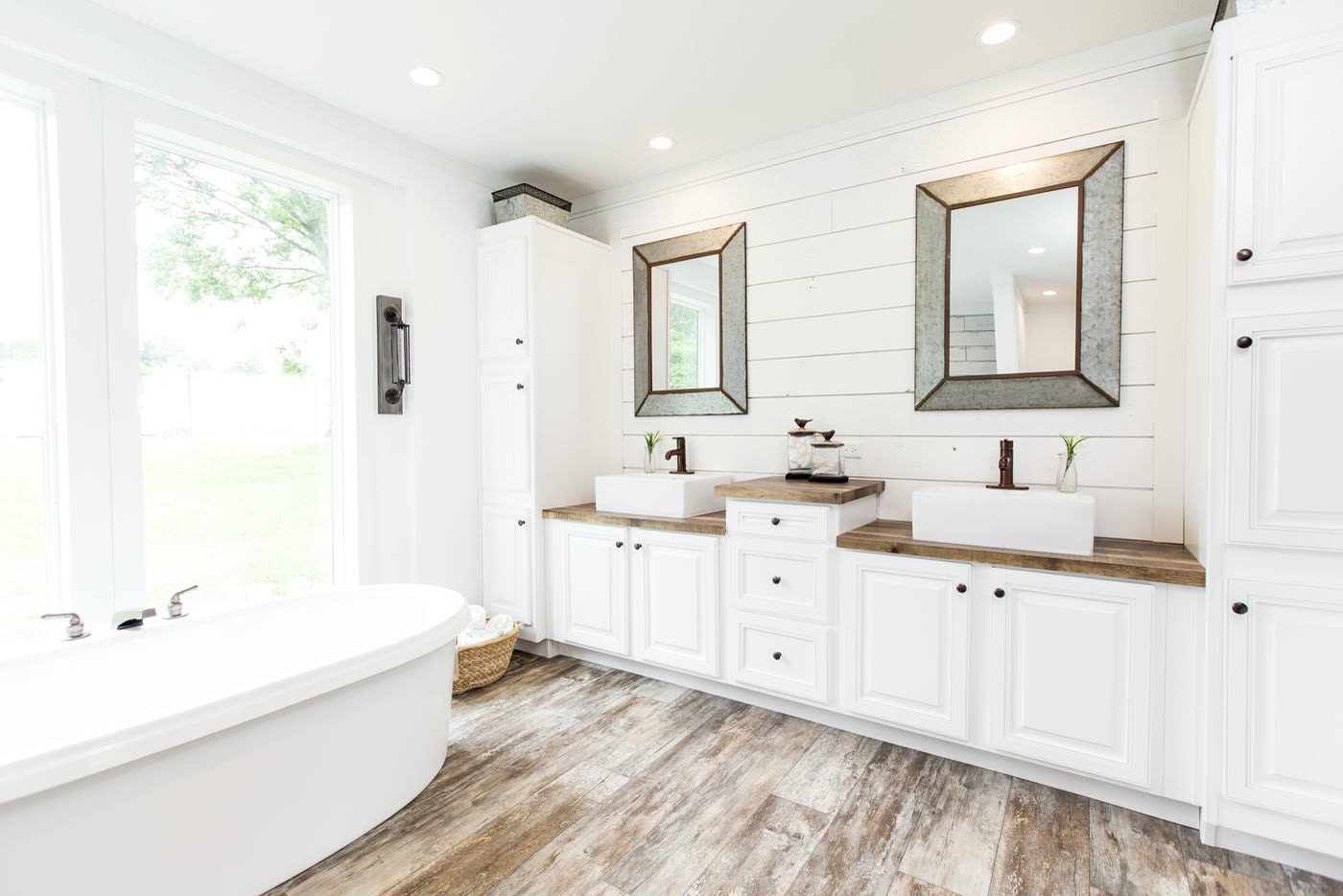 Primary bath, second furnishing. Double vessel sinks, tall cabinets, tub by the window.