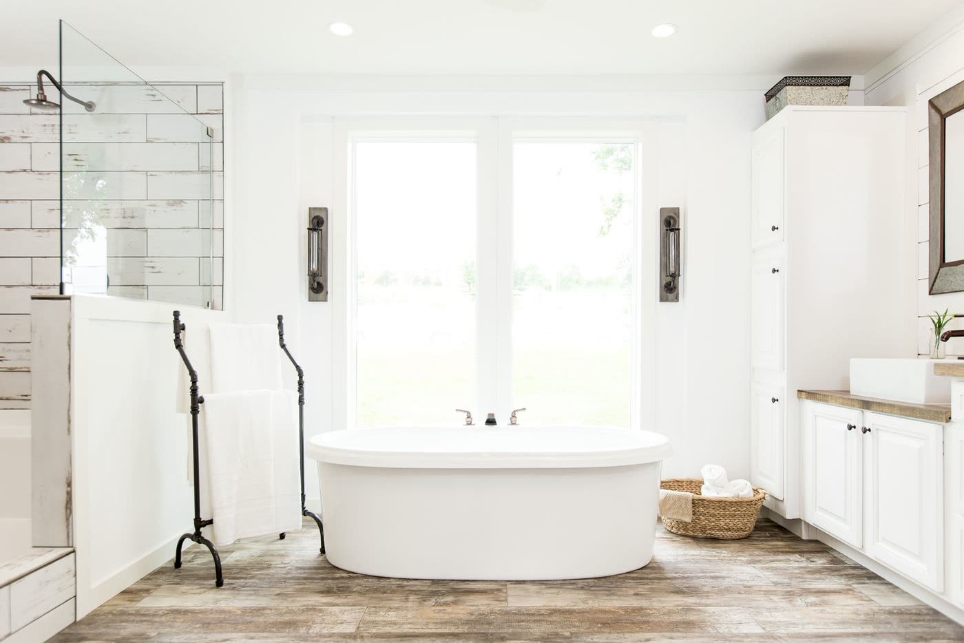 Primary bath, second furnishing. Freestanding tub at the window, tiled shower, vanity on the right.