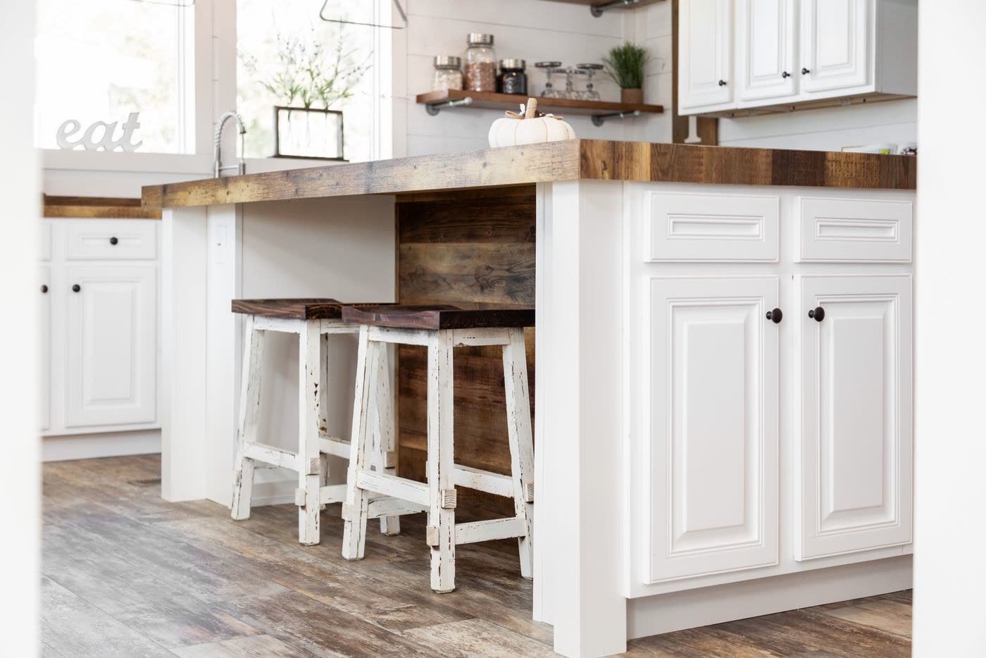Kitchen island. Butcher-block top, two stools, white cabinets.