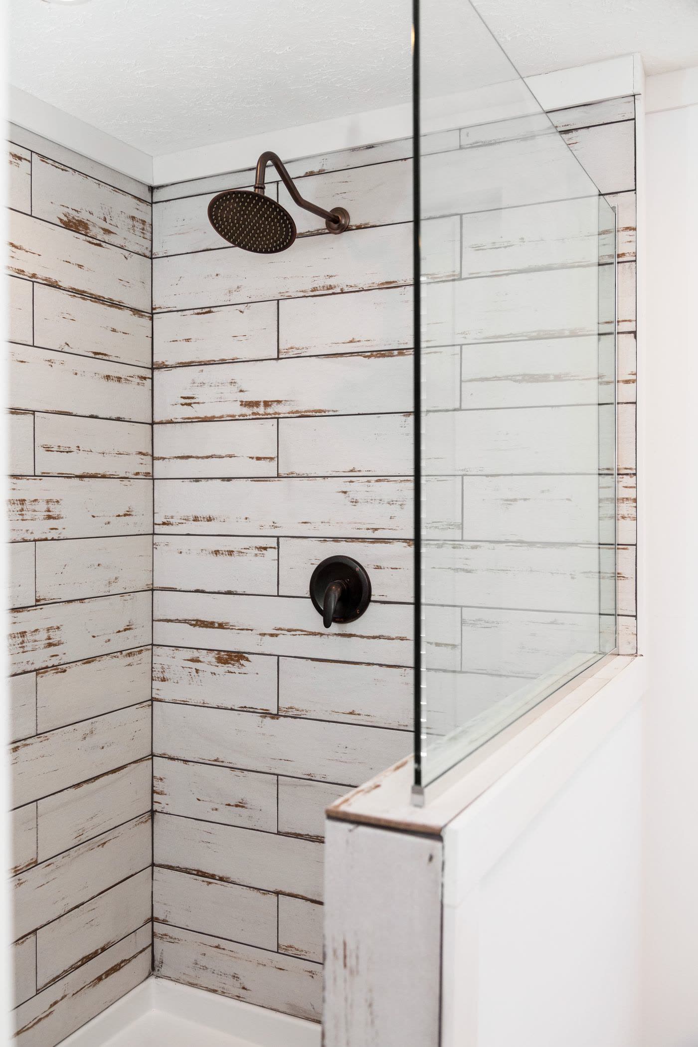 Primary bath. Rain shower head, tiled shower wall, glass panel.