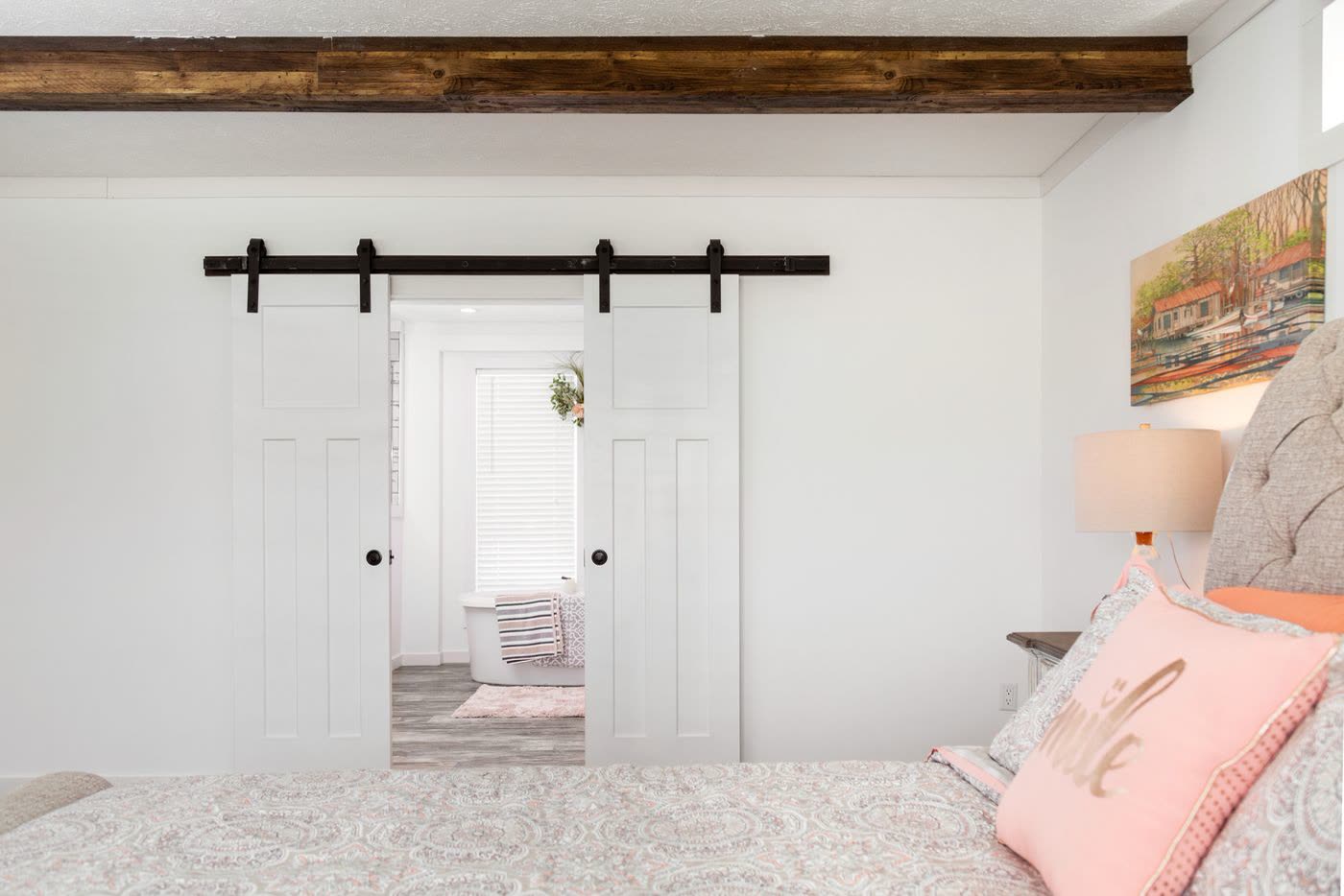 Primary bedroom. Barn door open to the bath, tub beyond.