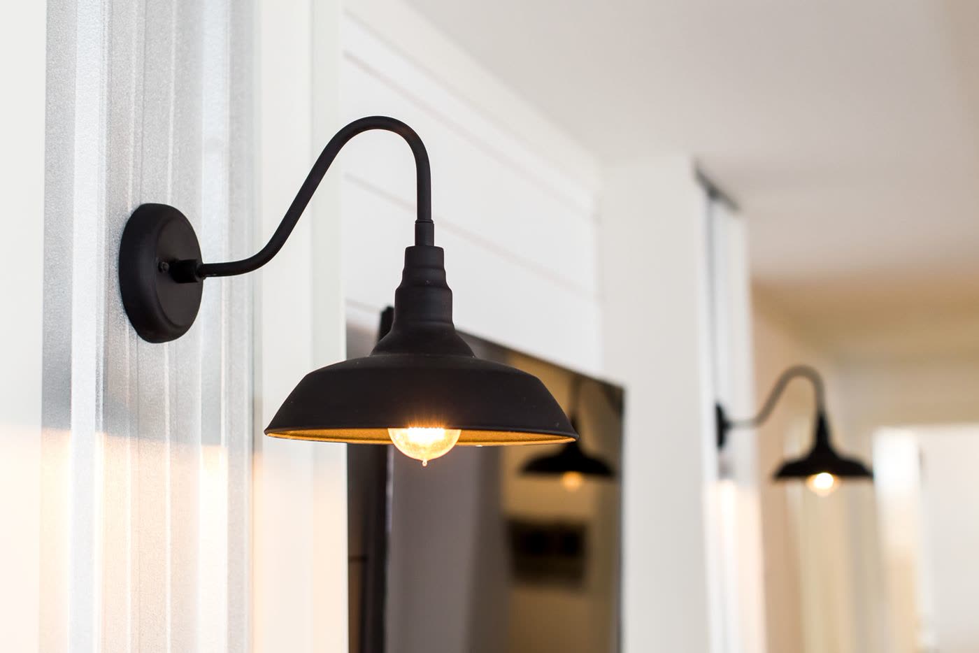 Detail. Black gooseneck sconce beside a window, second sconce down the hall.