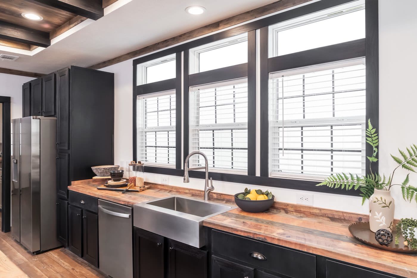 Kitchen. Farmhouse sink under three windows, wood-look counters, dishwasher.