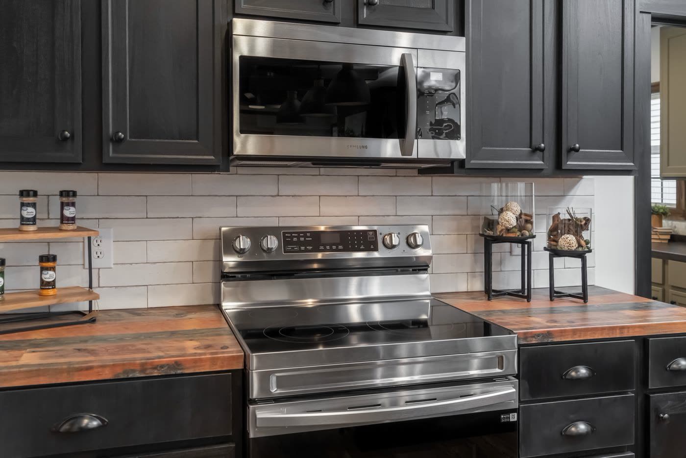 Kitchen. Stainless electric range, subway tile backsplash, spice shelves.